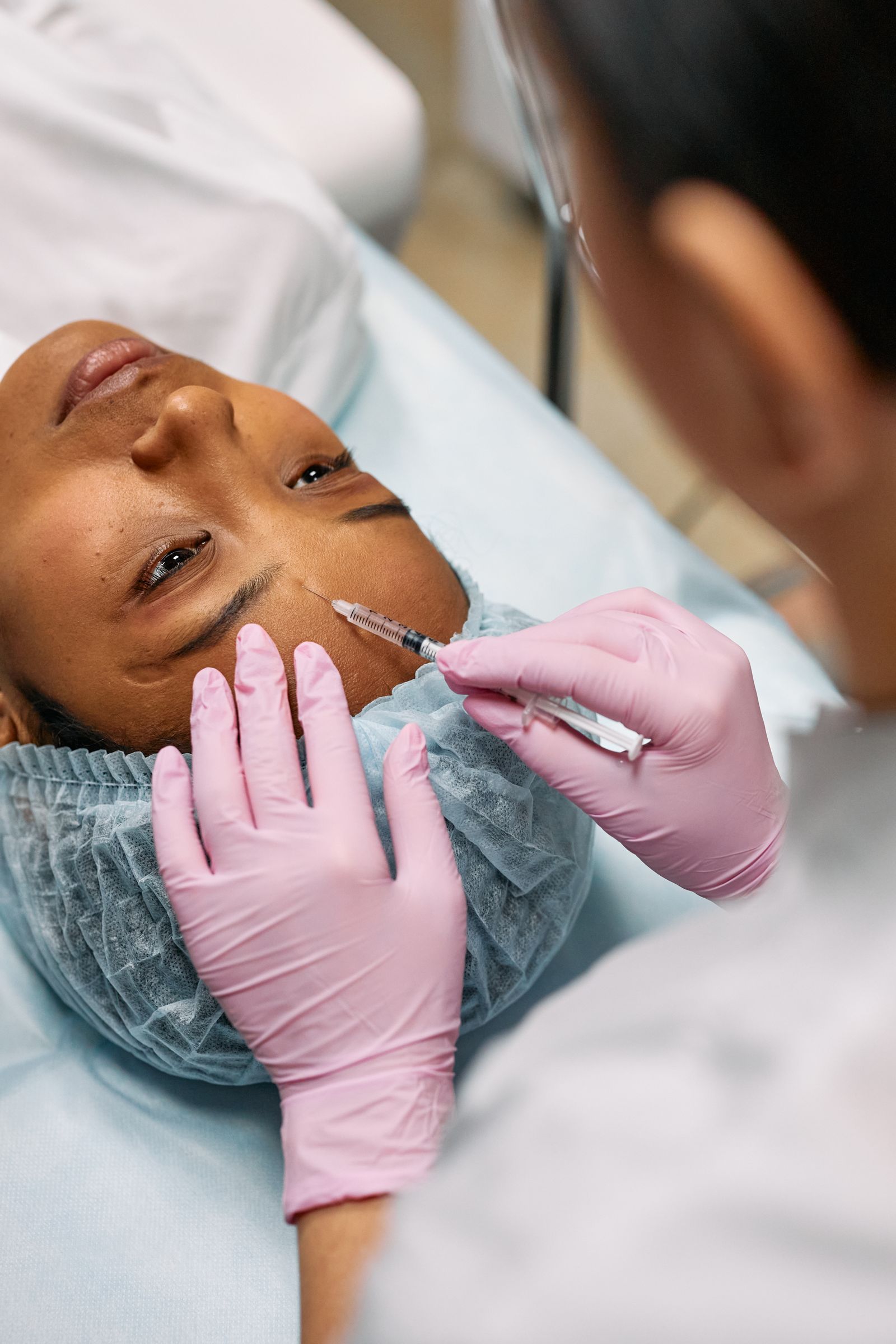 A cosmetic professional administering a Botox injection to a patient's forehead in a clinical setting