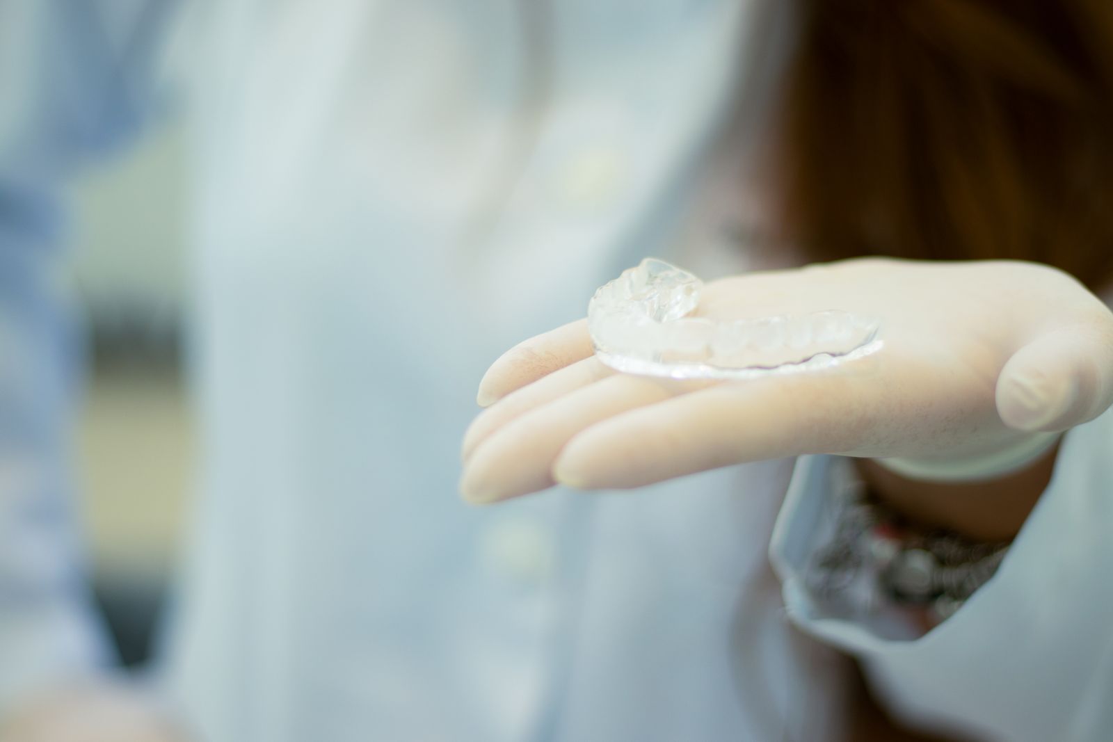 A gloved hand presenting a transparent custom mouth guard