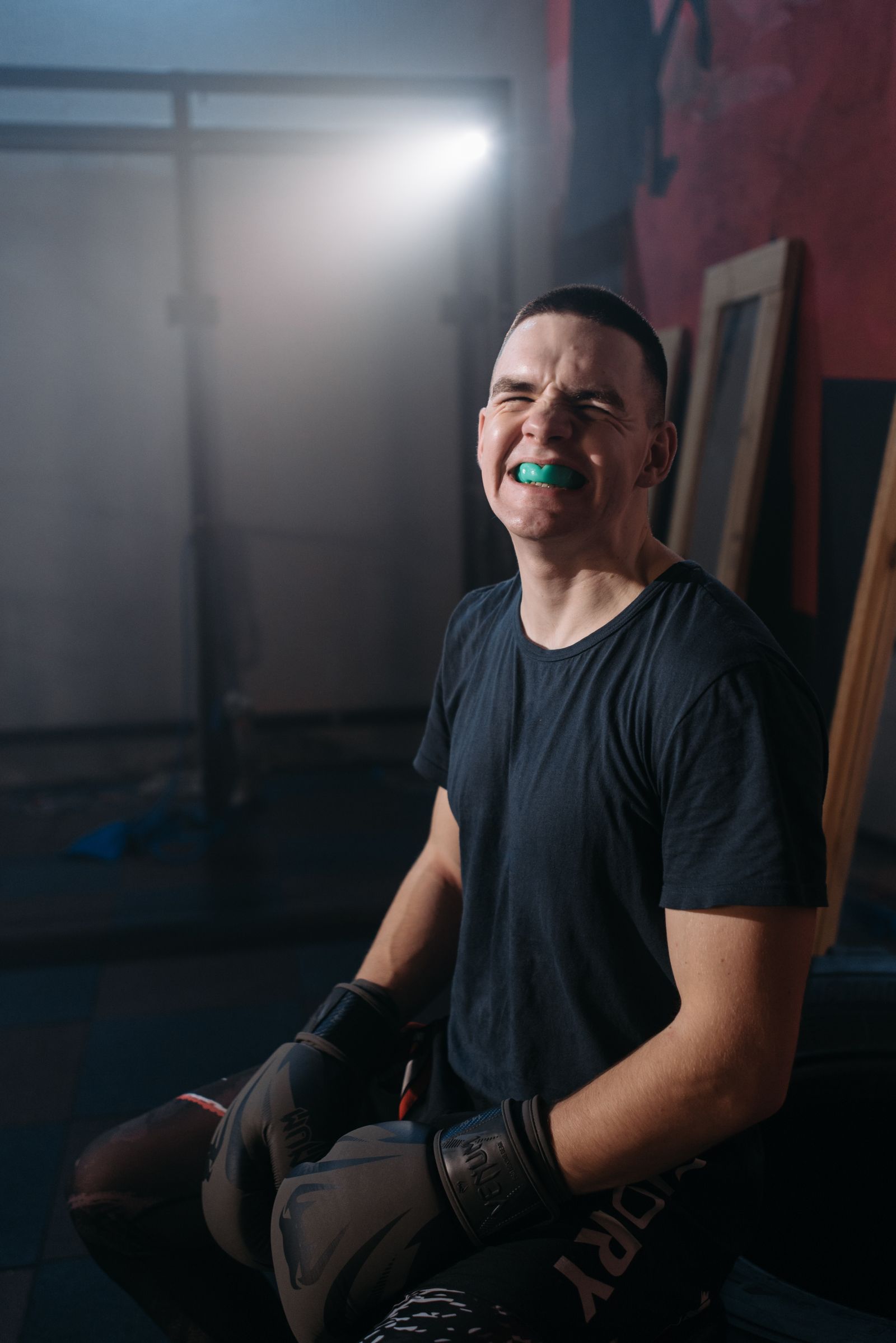 Young boxer wearing a sports mouth guard and gloves in a gym